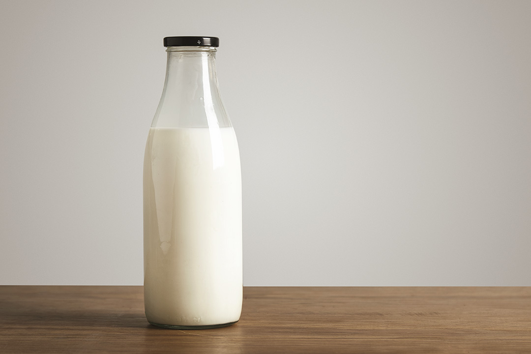 simple-vintage-bottle-filled-with-fresh-milk-on-thick-wooden-table-closed-with-black-cap-cafe-shop